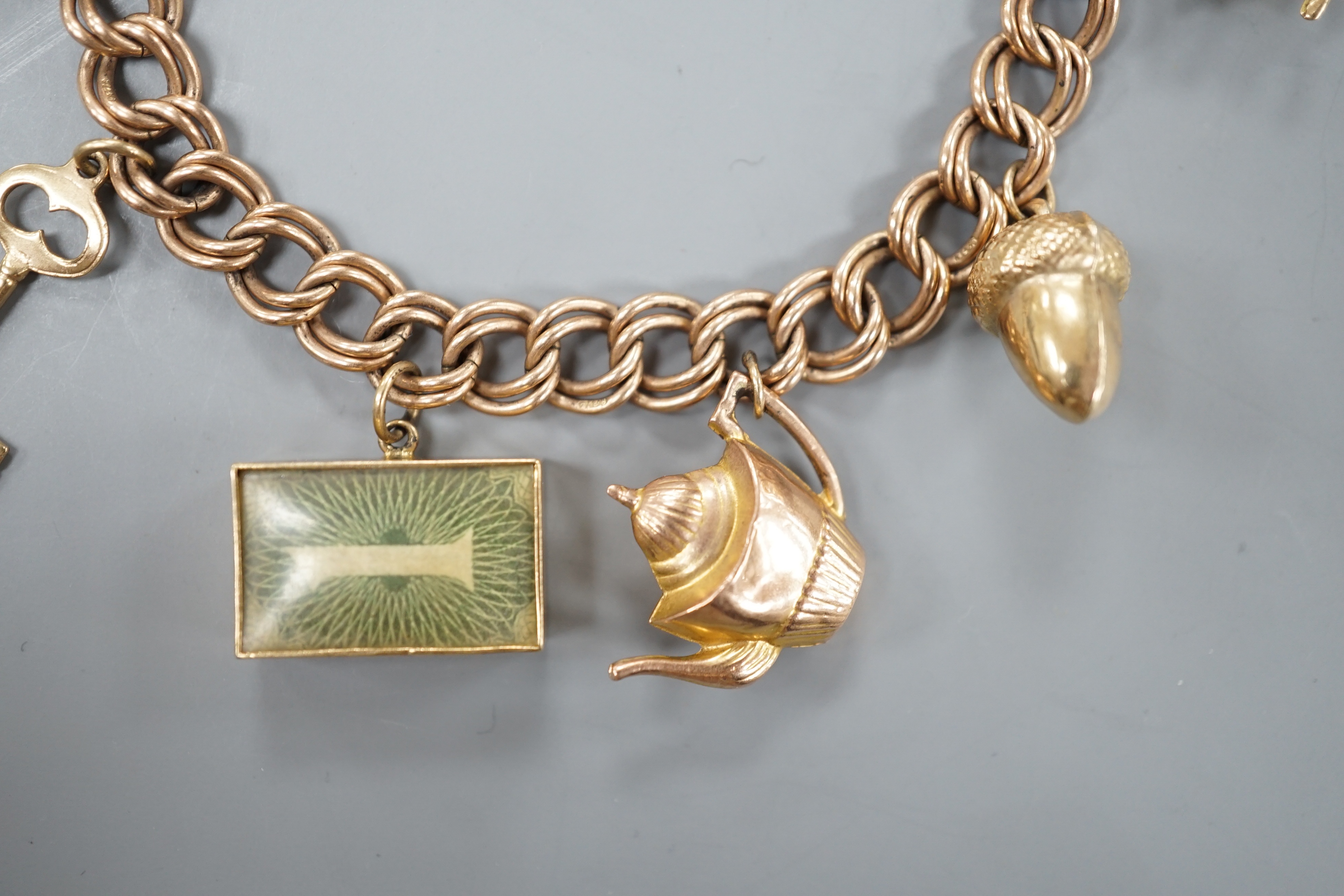 A 1960's 9ct gold charm bracelet, hung with eight assorted mainly 9ct gold charms and a 22ct gold wedding band, gross 28.4 grams.